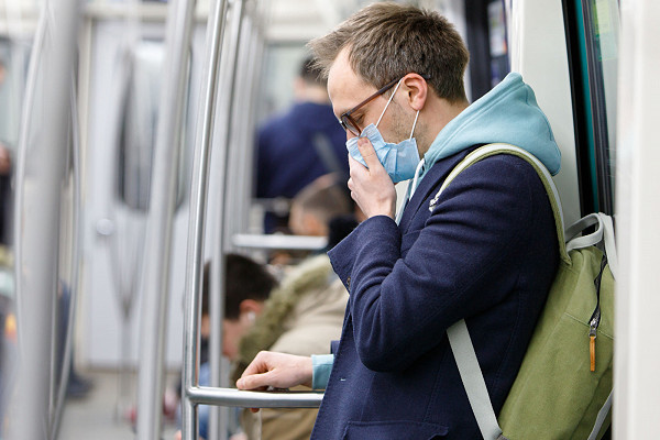 Young man an on a London tube wearing a mask to protect him from coronavirus