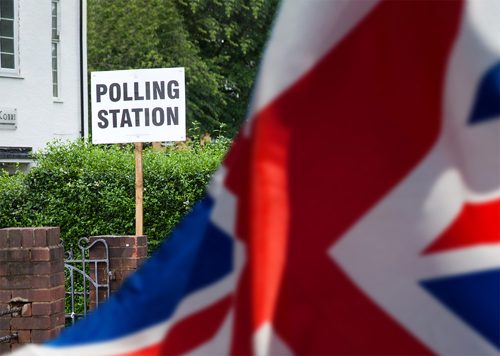Picture of polling station sign behind a union jack flag