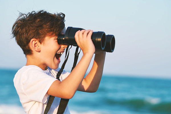 A young boy looking through binoculars